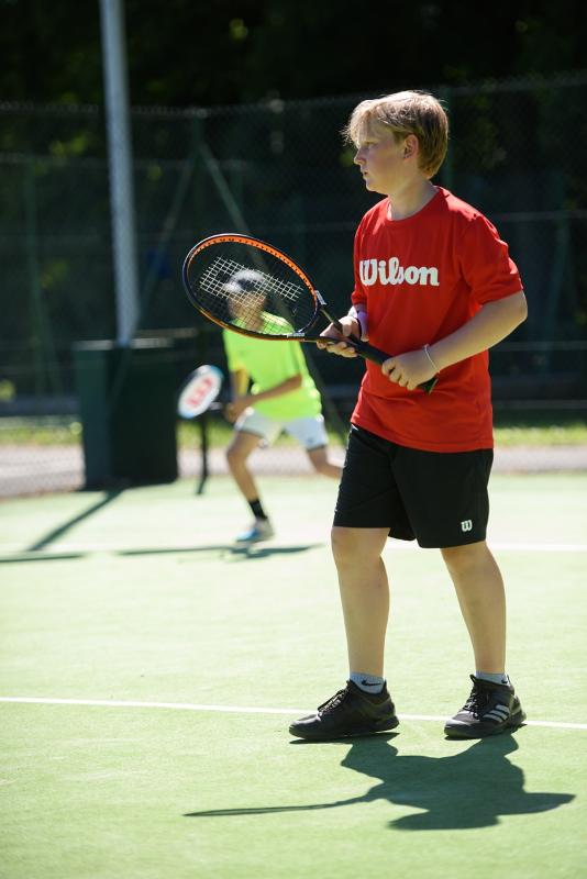 Twee jongens staan op een tennisveld tijdens een taalreis engels