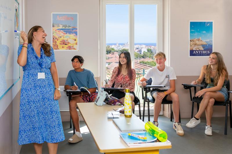Een docent lacht samen met jongeren in een lokaal tijdens een taalreis frans
