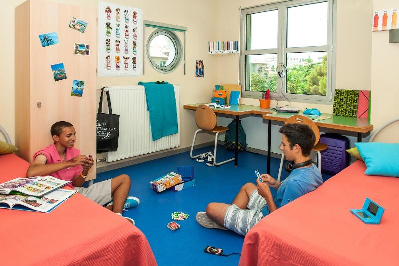 Twee jongens spelen uno op de grond van een slaapkamer tijdens een taalreis frans