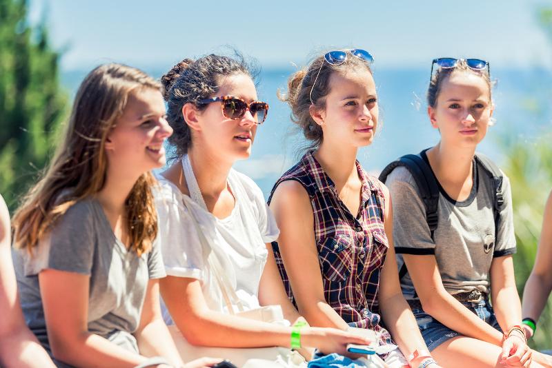 Vier meisjes zitten buiten met zonnebrillen op tijdens een taalreis frans