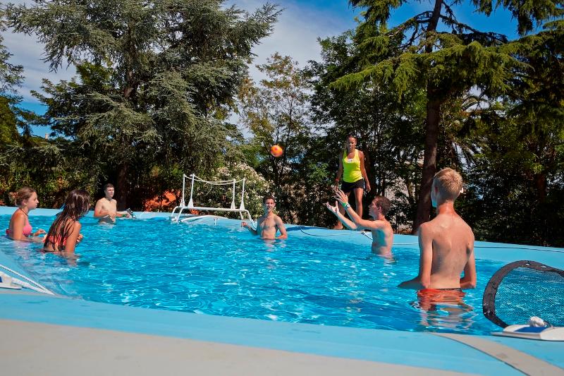 Jongeren spelen met een bal in een buitenzwembad tijdens een taalreis frans