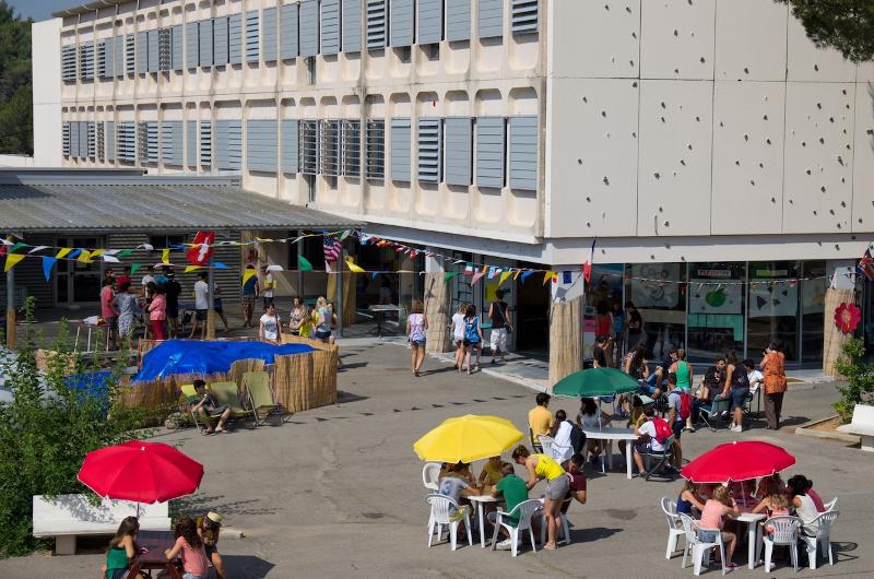 Een school met een plein met tafels, stoelen en parasols tijdens een taalreis frans