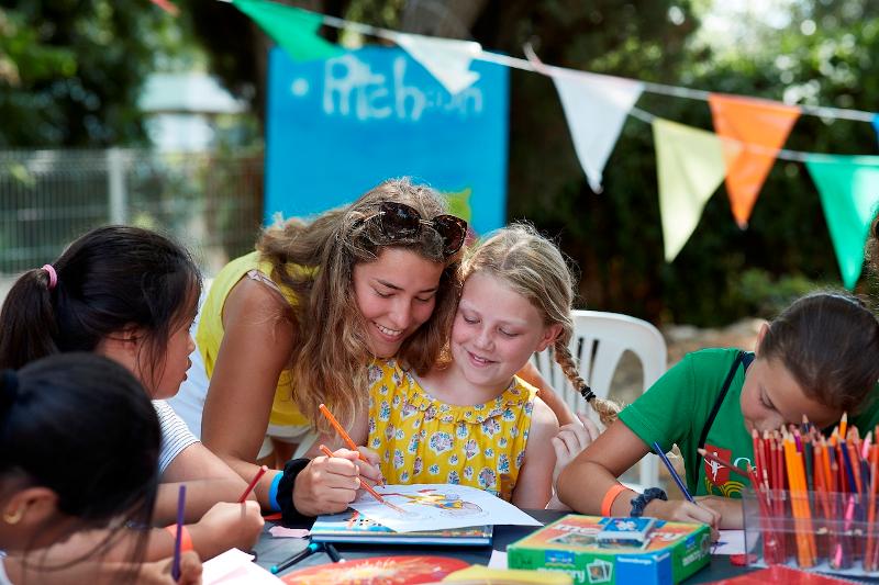 Een docent helpt een meisje met tekenen tijdens een taalreis frans