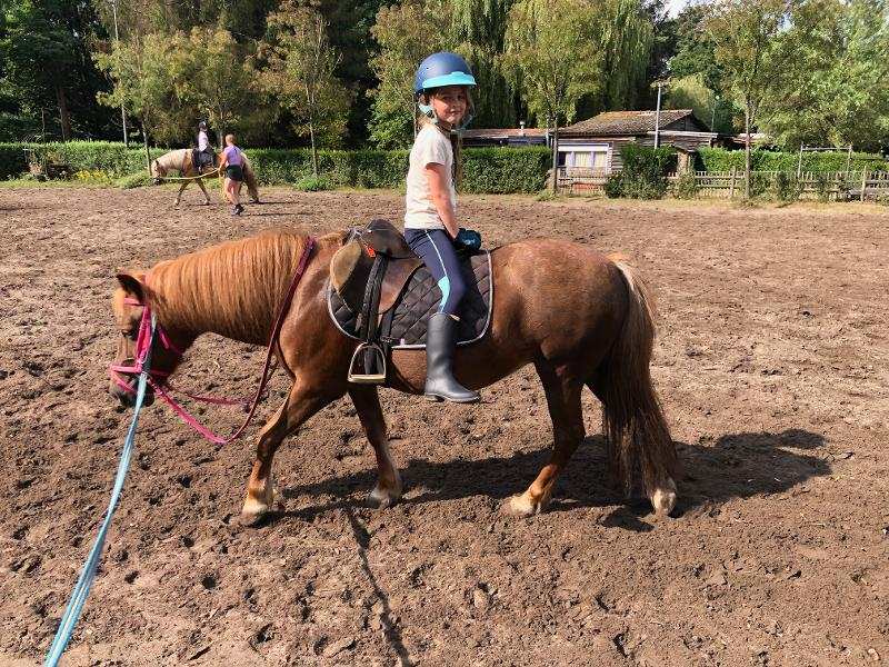 Kind zit op een pony op ponykamp België