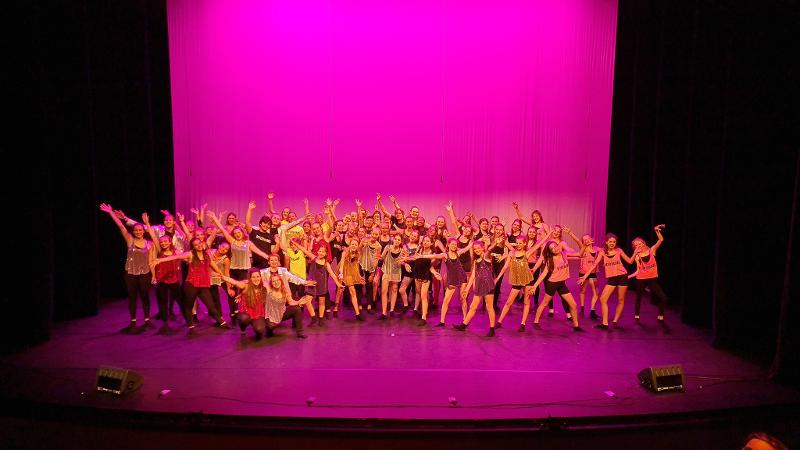 Podiumfoto in roze licht tijdens het musicalkamp