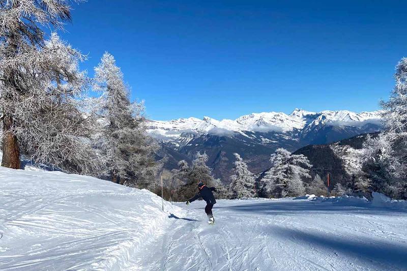 Deelnemer van de jongeren groepsreis wintersport daalt van de berg af met een snowboard