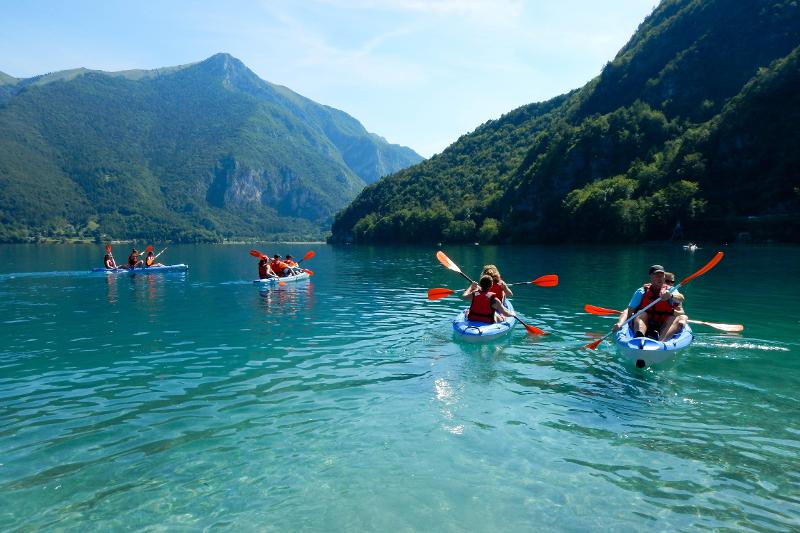 Deelnemers van groepsreis Italië kajakken in een helderblauw meer