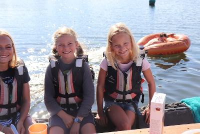 Drie meisjes poseren vanop de oever langs het meer
