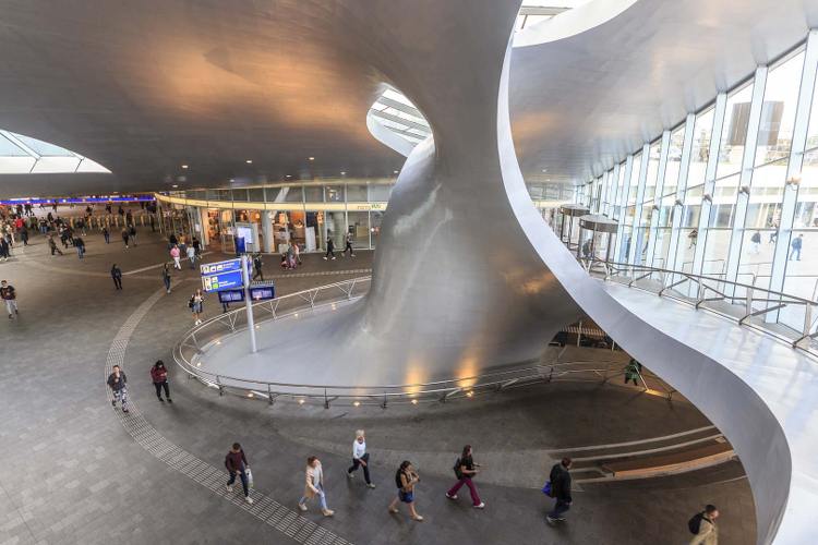 Reizigers wandelen door de stationshal van Arnhem. 
