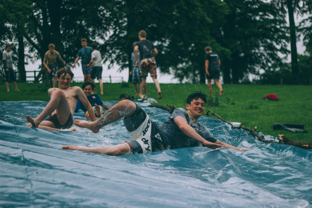 Kinderen van jonge leeftijd glijden van een zelfgemaakte sliding tijdens een kamp in het buitenland