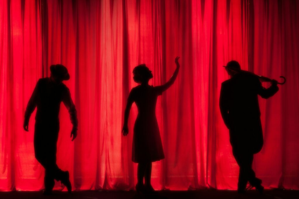 drie mensen voor een rood doek tijdens een theater zomerkamp activiteit ideeën