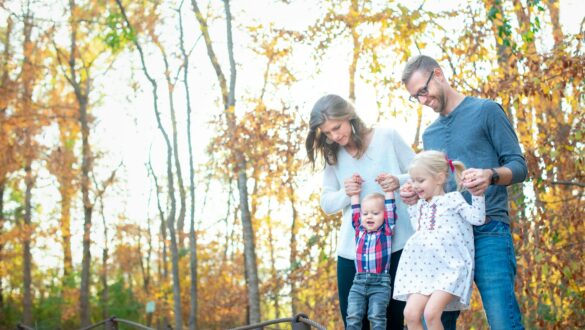 Ouders zijn met hun kinderen in het bos een activiteit aan het doen tijdens de herfstvakantie